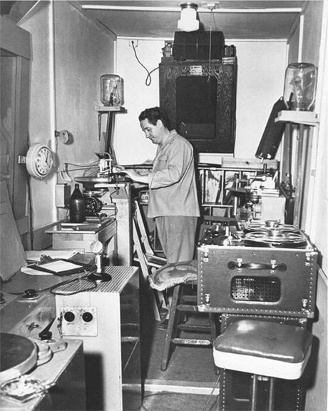 Les Paul in his workshop with an Ampex reel tape recorder